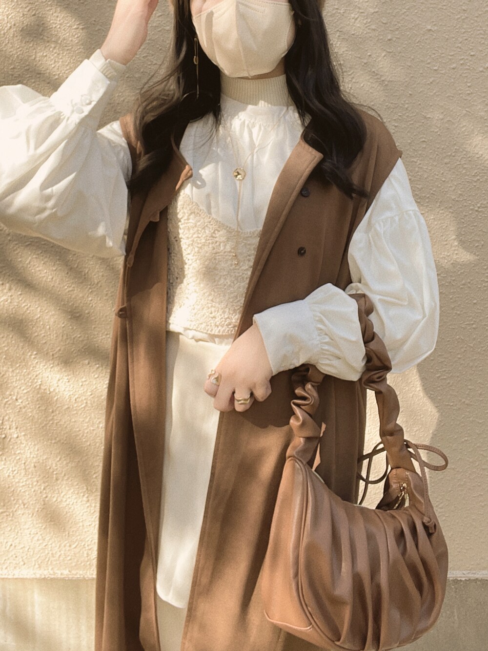 ホワイト系のシャツ/ブラウス、ベージュ系のニット/セーター、ブラウン系のハンドバッグを着用したレディースの冬コーディネートの4枚目の写真