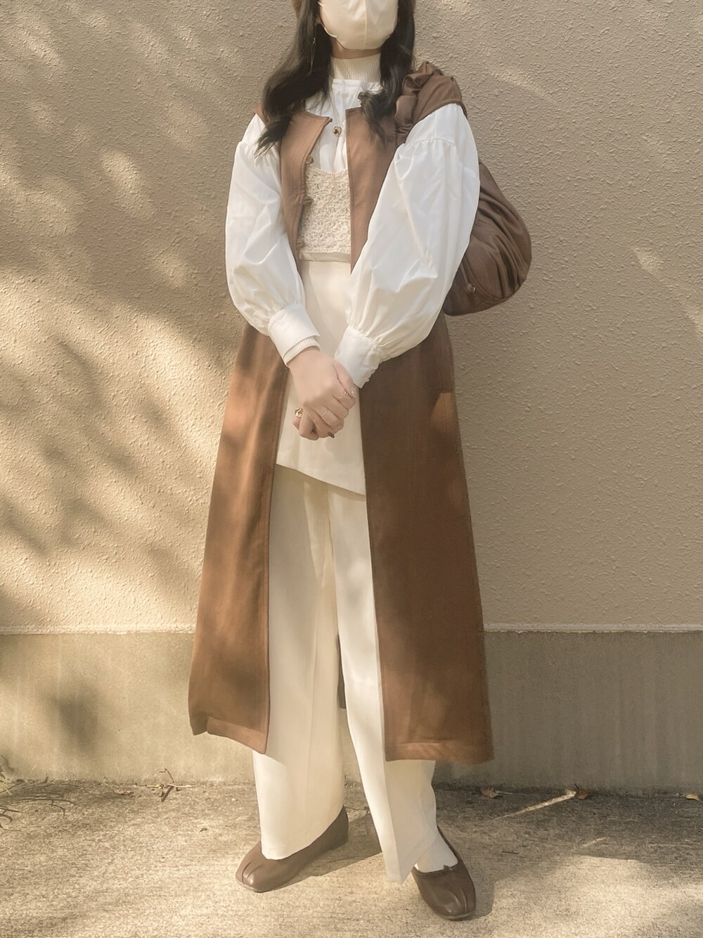 ホワイト系のシャツ/ブラウス、ベージュ系のニット/セーター、ブラウン系のハンドバッグを着用したレディースの冬コーディネートの2枚目の写真