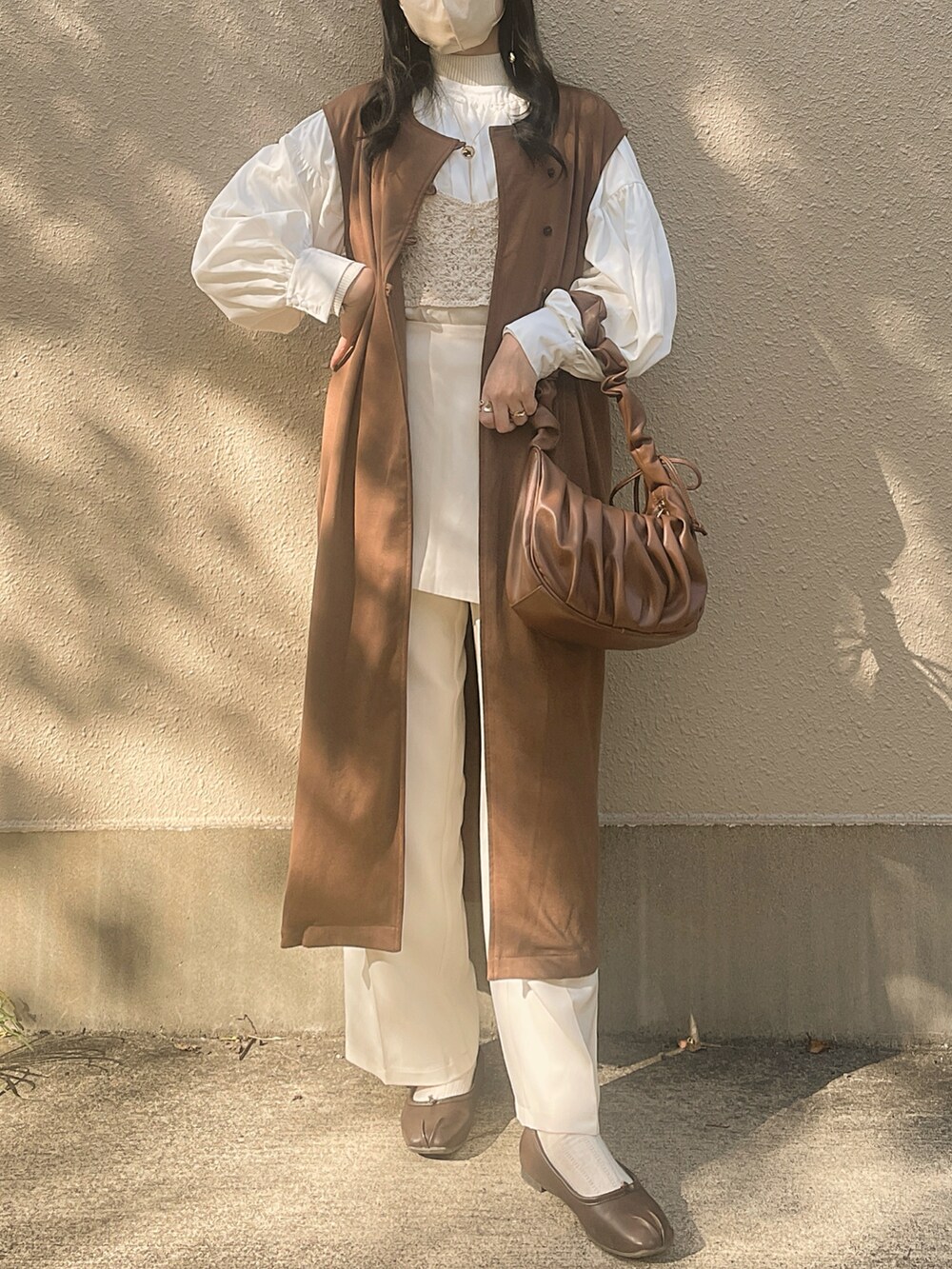 ホワイト系のシャツ/ブラウス、ベージュ系のニット/セーター、ブラウン系のハンドバッグを着用したレディースの冬コーディネートの3枚目の写真