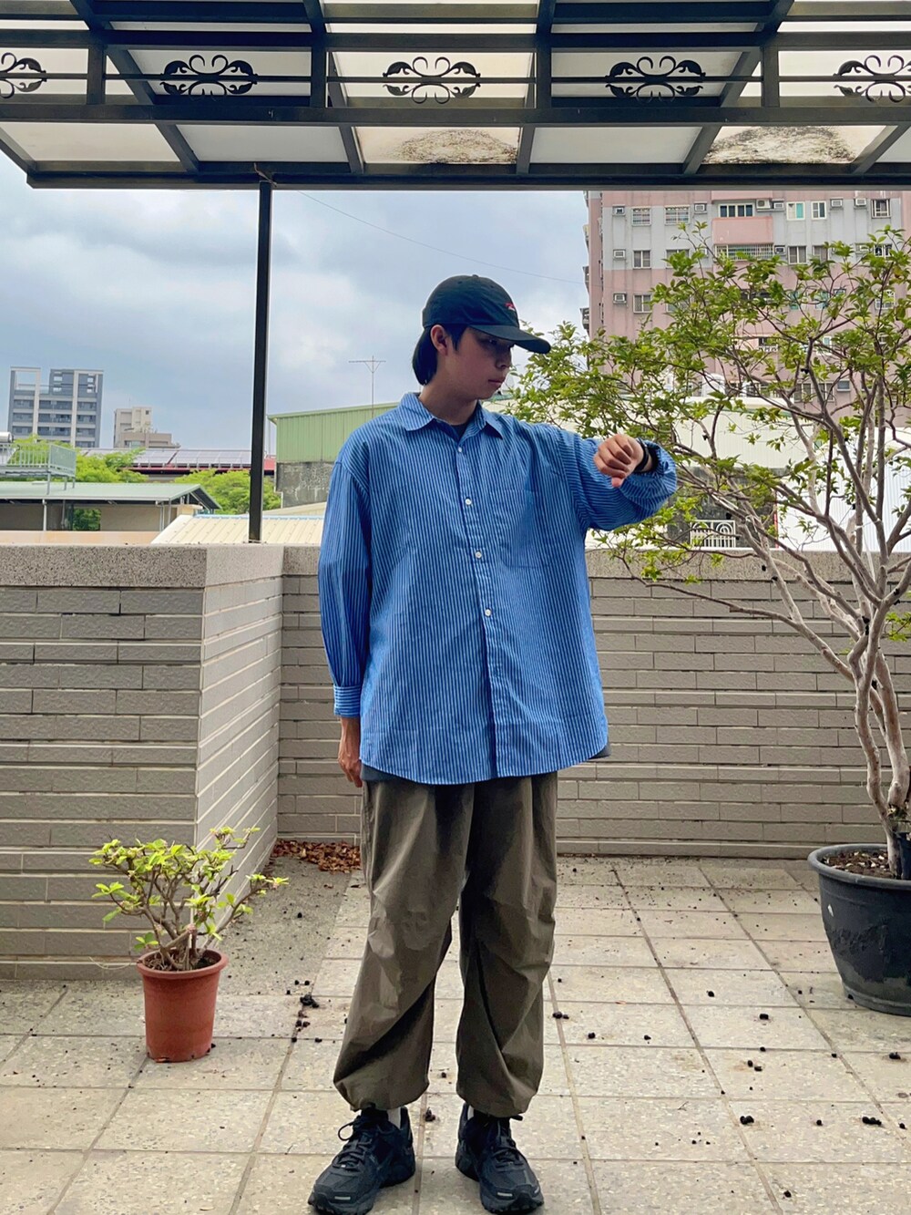 ブルー系のシャツ/ブラウス、ブラック系のスニーカー、グリーン系のチノパンツを着用したメンズの春コーディネートの2枚目の写真