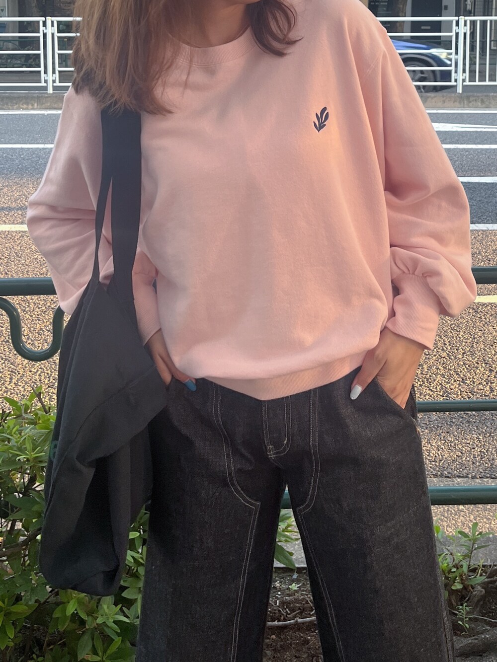 ピンク系のスウェット、ブラック系のデニムパンツ、ブラック系のトートバッグを着用したレディースの夏コーディネートの2枚目の写真