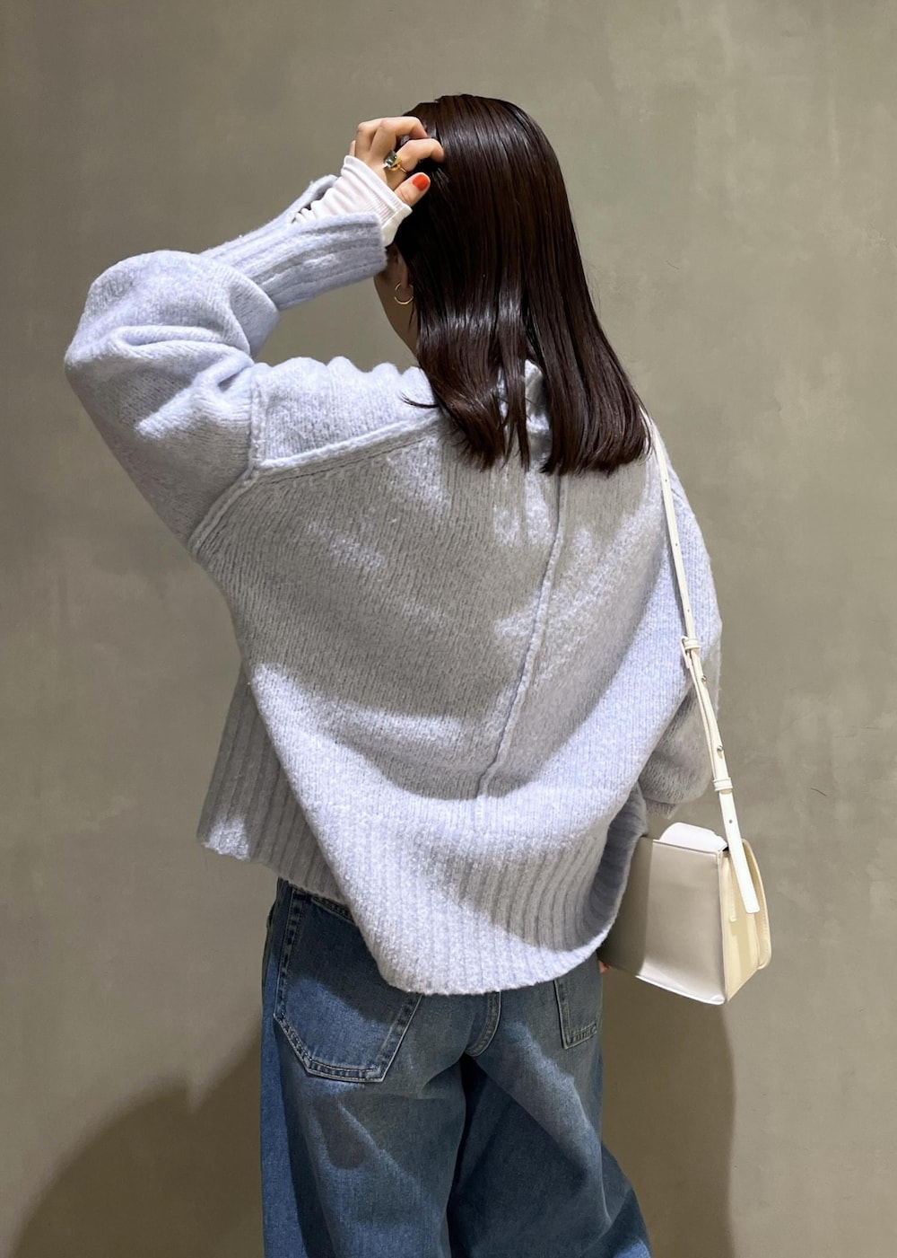 ブルー系のニット/セーター、ブルー系のデニムパンツ、ホワイト系のTシャツ/カットソーを着用したレディースの秋コーディネートの7枚目の写真