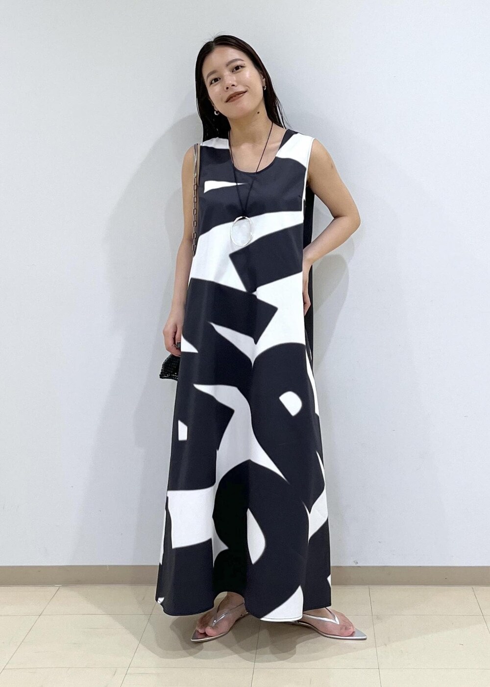 ブラック系のハンドバッグ、シルバー系のサンダル、ブラック系のワンピースを着用したレディースの夏コーディネートの2枚目の写真