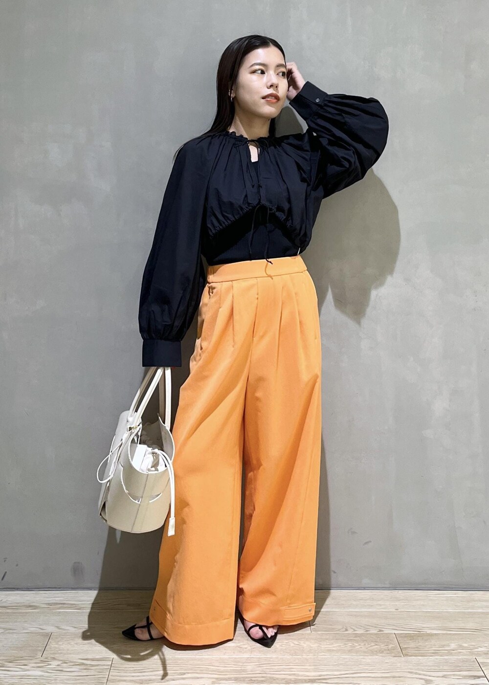 ブラック系のサンダル、ホワイト系のトートバッグ、オレンジ系のその他パンツを着用したレディースの春コーディネートの2枚目の写真