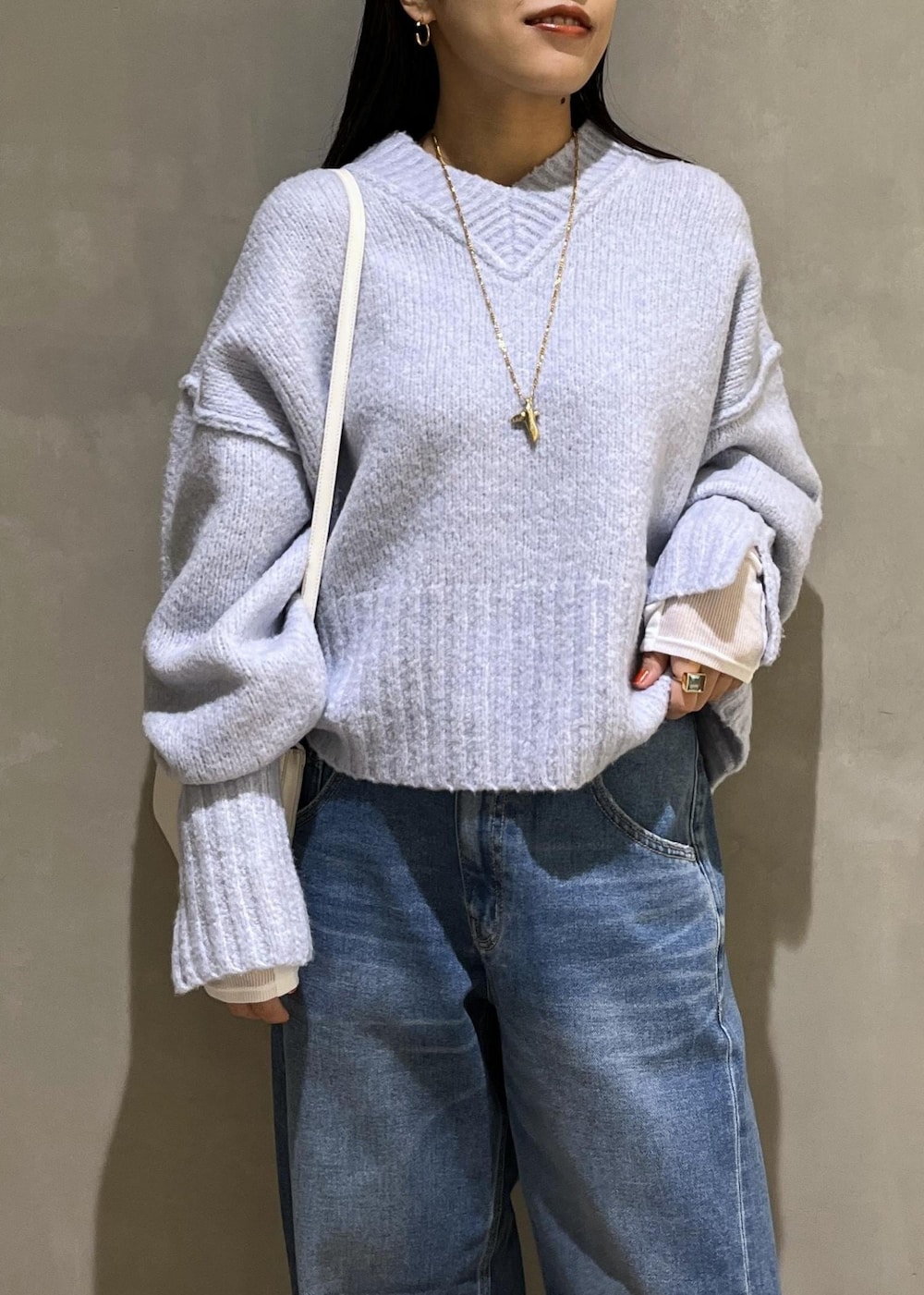 ブルー系のニット/セーター、ブルー系のデニムパンツ、ホワイト系のTシャツ/カットソーを着用したレディースの秋コーディネートの6枚目の写真