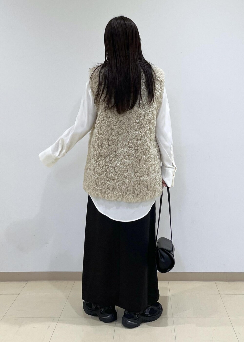 ベージュ系のその他アウター、ブラック系のショルダーバッグ、ブラック系のスニーカーを着用したレディースの秋コーディネートの5枚目の写真