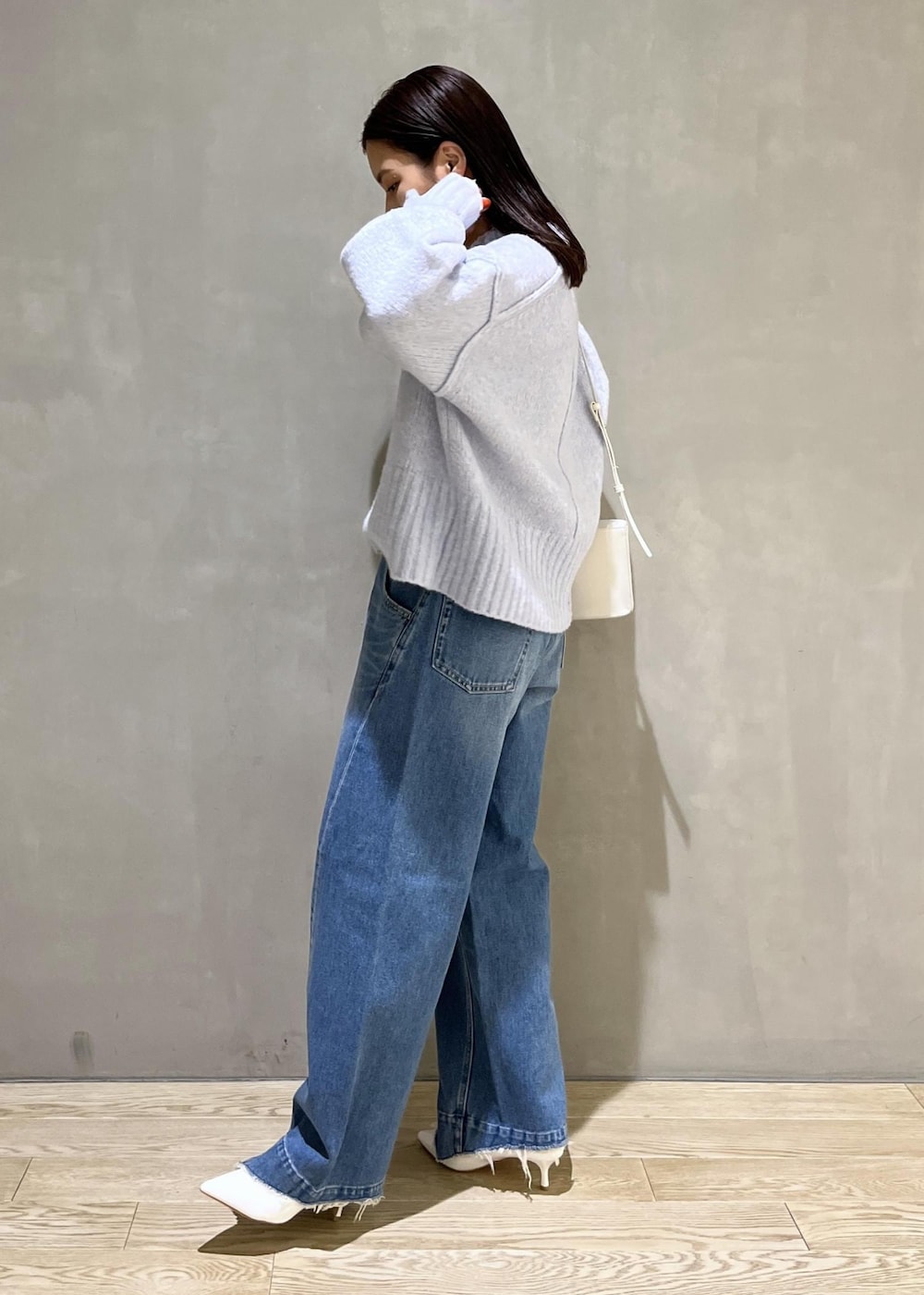 ブルー系のニット/セーター、ブルー系のデニムパンツ、ホワイト系のTシャツ/カットソーを着用したレディースの秋コーディネートの3枚目の写真