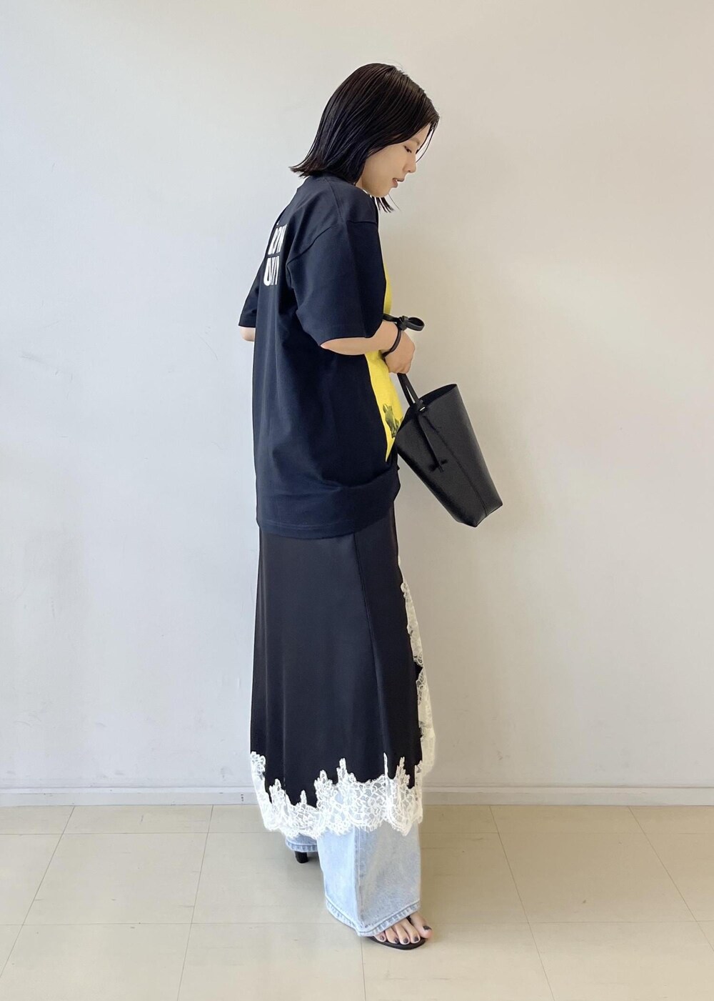 ブラック系のスカート、ブラック系のショルダーバッグ、グレー系のTシャツ/カットソーを着用したレディースの夏コーディネートの6枚目の写真