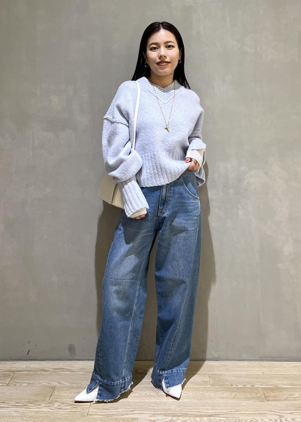 ブルー系のニット/セーター、ブルー系のデニムパンツ、ホワイト系のTシャツ/カットソーを着用したレディースの秋コーディネートの2枚目の写真