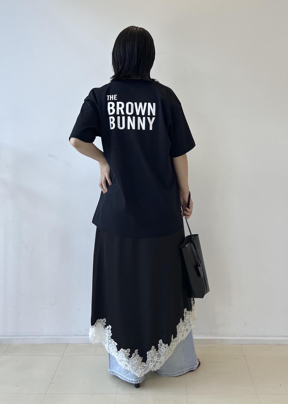 ブラック系のスカート、ブラック系のショルダーバッグ、グレー系のTシャツ/カットソーを着用したレディースの夏コーディネートの5枚目の写真