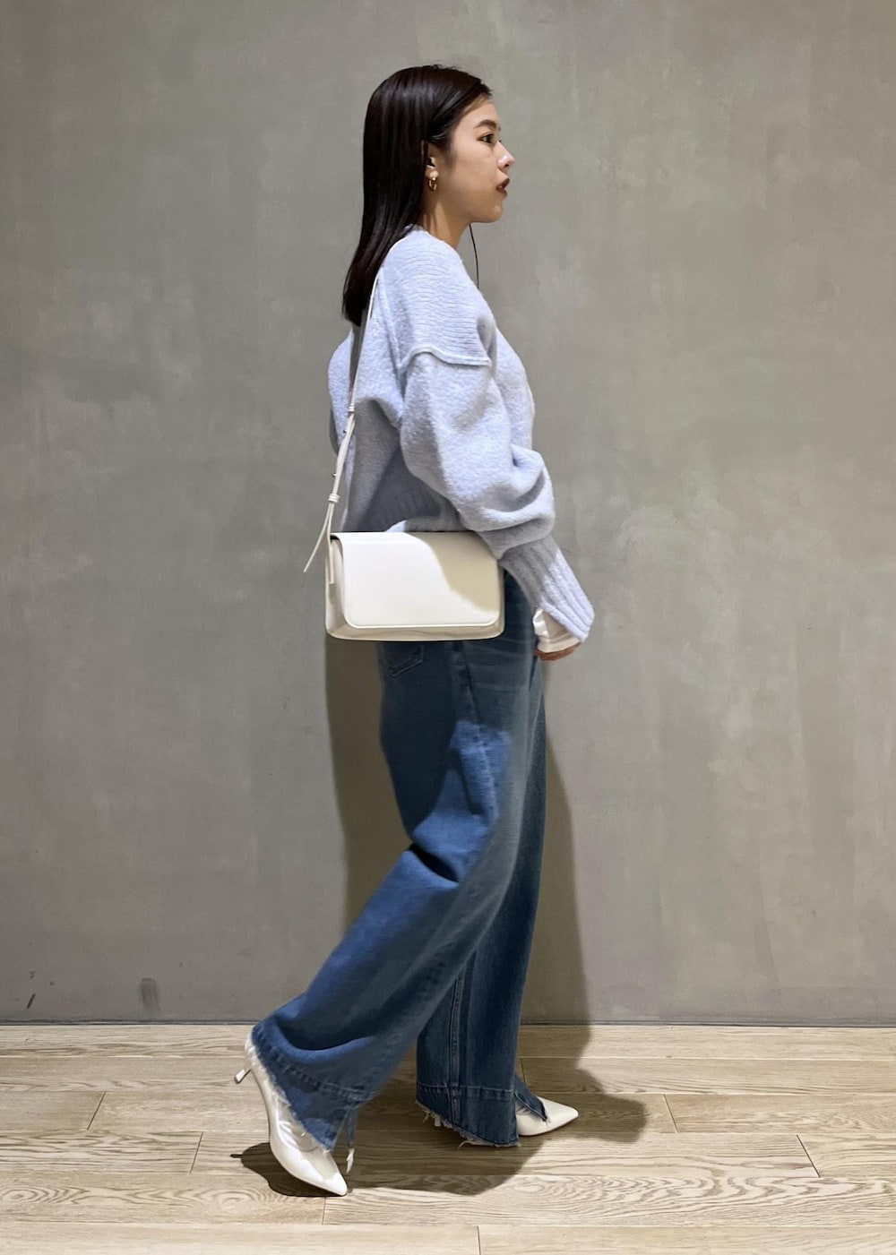 ブルー系のニット/セーター、ブルー系のデニムパンツ、ホワイト系のTシャツ/カットソーを着用したレディースの秋コーディネートの5枚目の写真