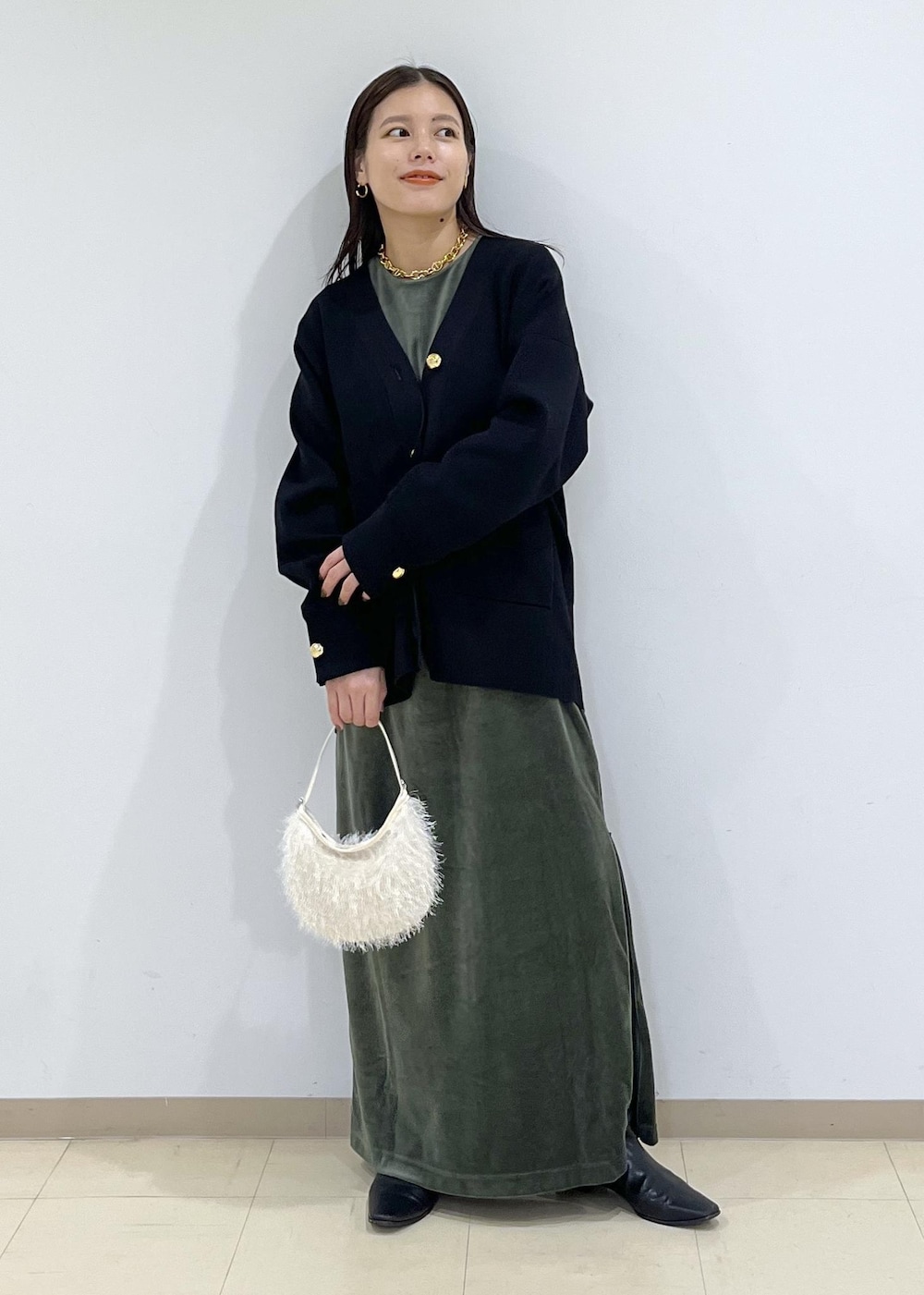 ブラック系のカーディガン/ボレロ、グリーン系のワンピース、ホワイト系のショルダーバッグを着用したレディースの秋コーディネートの2枚目の写真