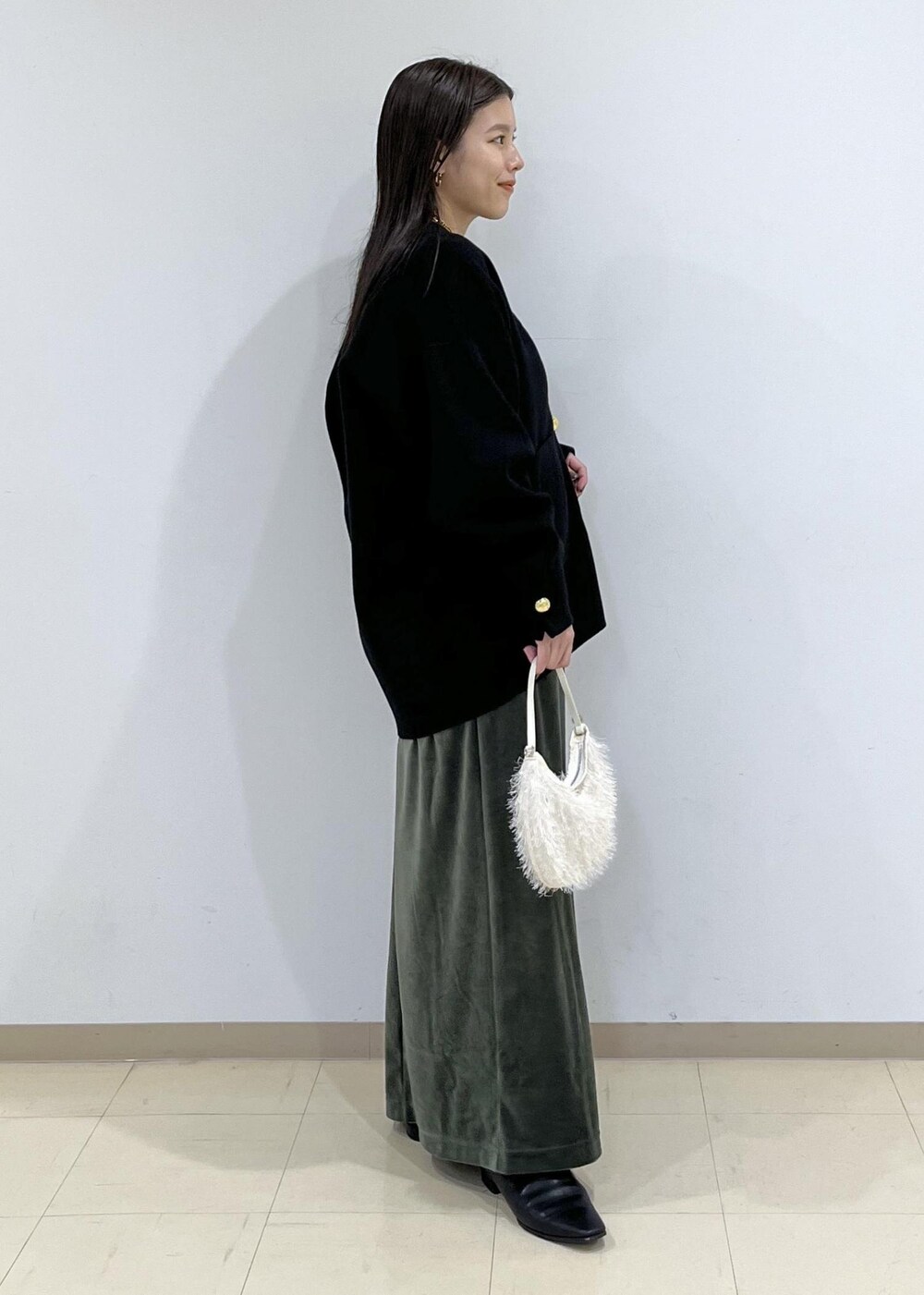 ブラック系のカーディガン/ボレロ、グリーン系のワンピース、ホワイト系のショルダーバッグを着用したレディースの秋コーディネートの6枚目の写真