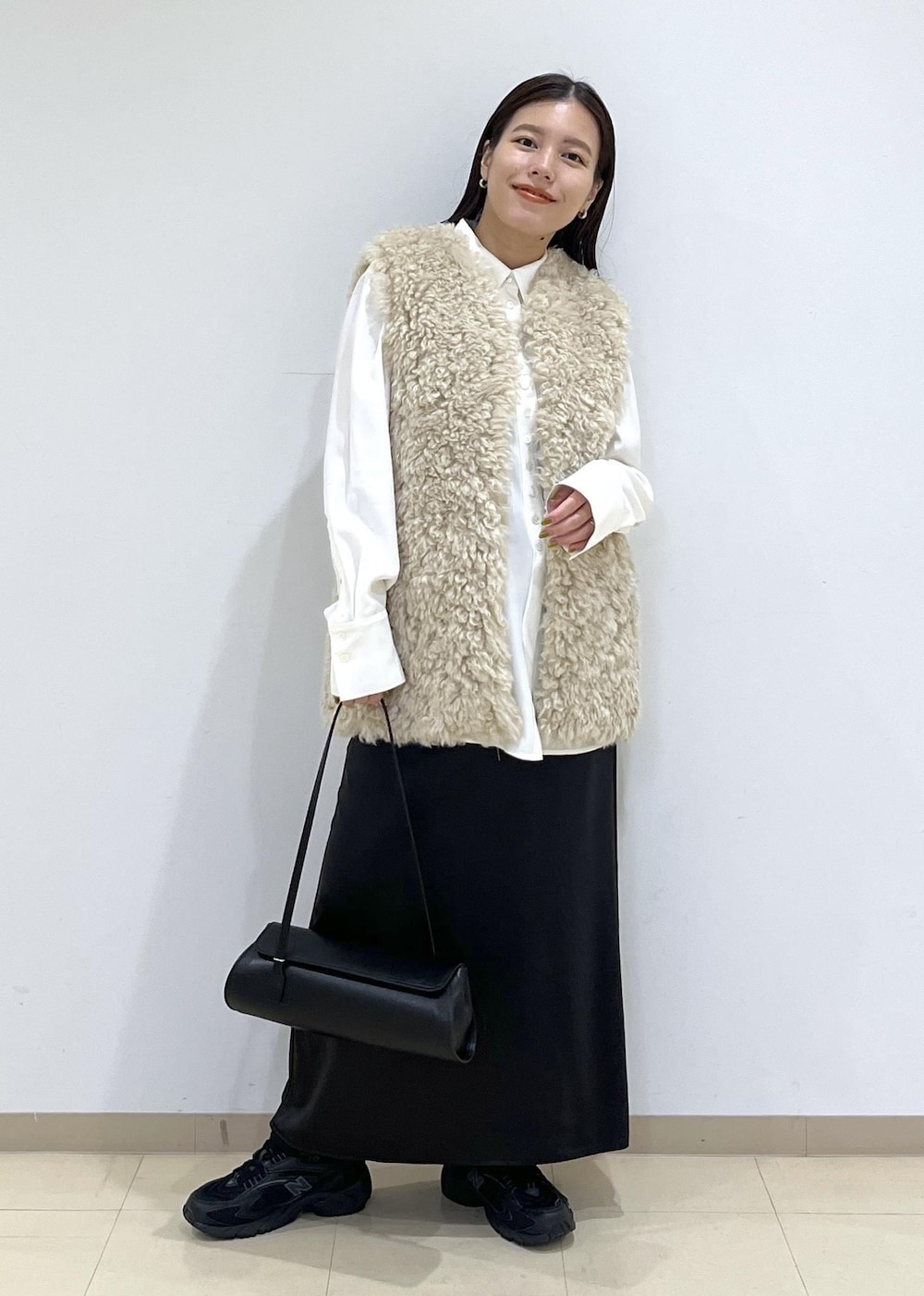 ベージュ系のその他アウター、ブラック系のショルダーバッグ、ブラック系のスニーカーを着用したレディースの秋コーディネートの2枚目の写真