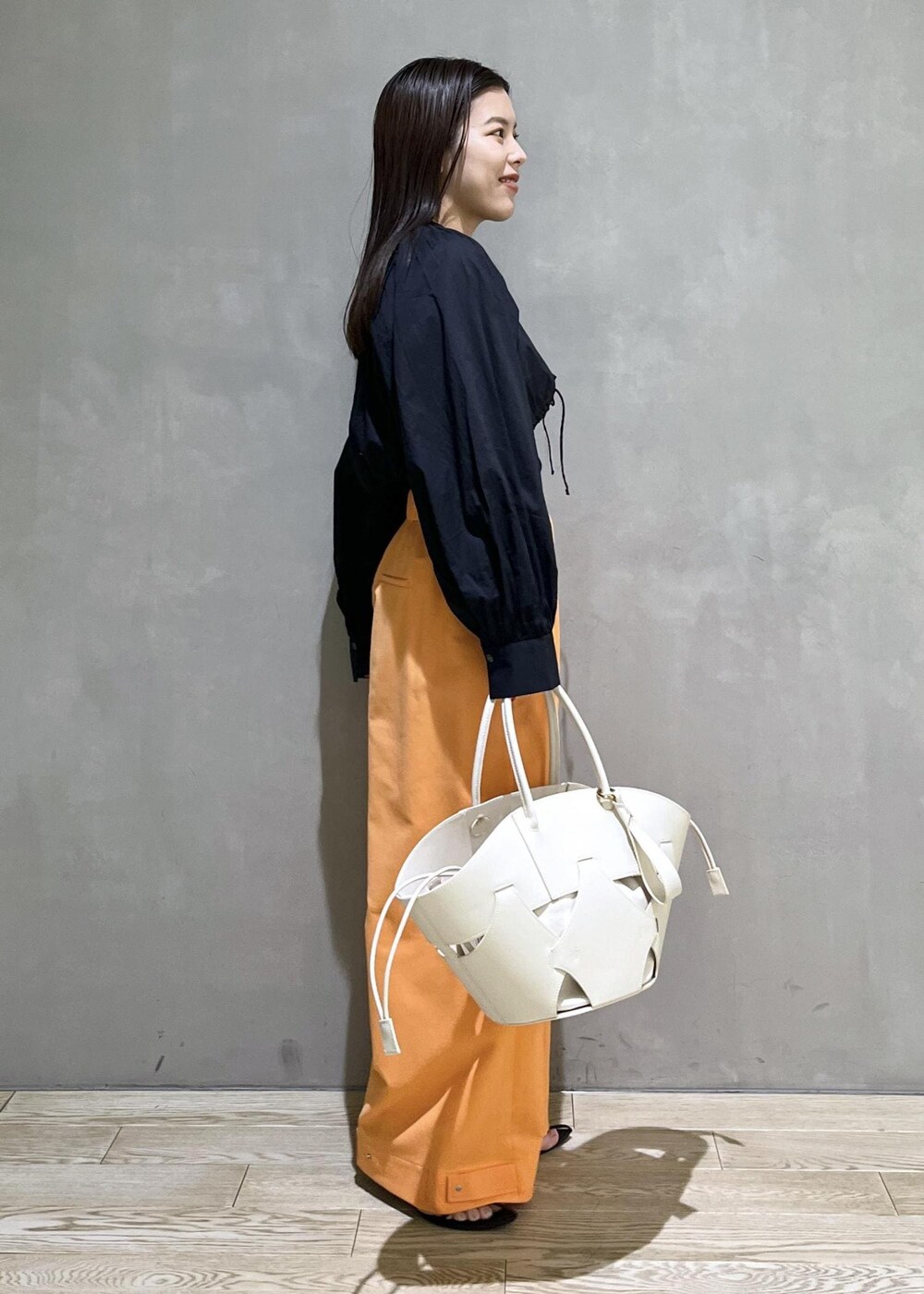 ブラック系のサンダル、ホワイト系のトートバッグ、オレンジ系のその他パンツを着用したレディースの春コーディネートの5枚目の写真