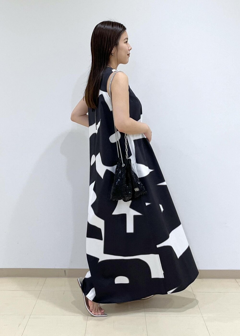 ブラック系のハンドバッグ、シルバー系のサンダル、ブラック系のワンピースを着用したレディースの夏コーディネートの5枚目の写真