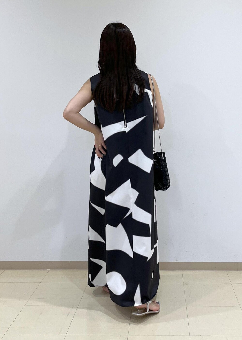 ブラック系のハンドバッグ、シルバー系のサンダル、ブラック系のワンピースを着用したレディースの夏コーディネートの4枚目の写真