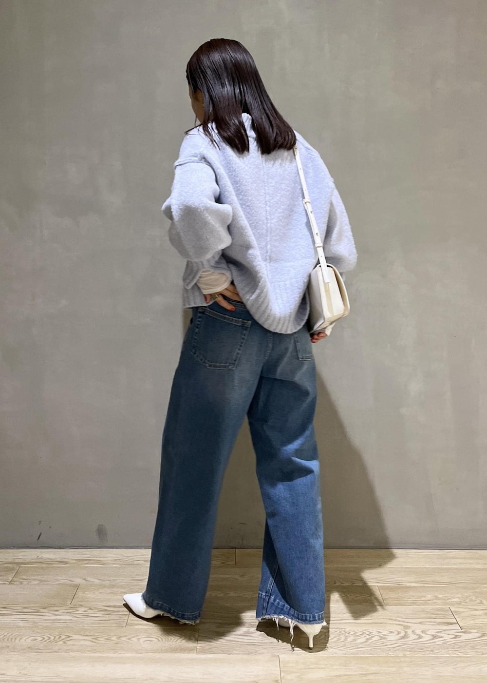 ブルー系のニット/セーター、ブルー系のデニムパンツ、ホワイト系のTシャツ/カットソーを着用したレディースの秋コーディネートの4枚目の写真