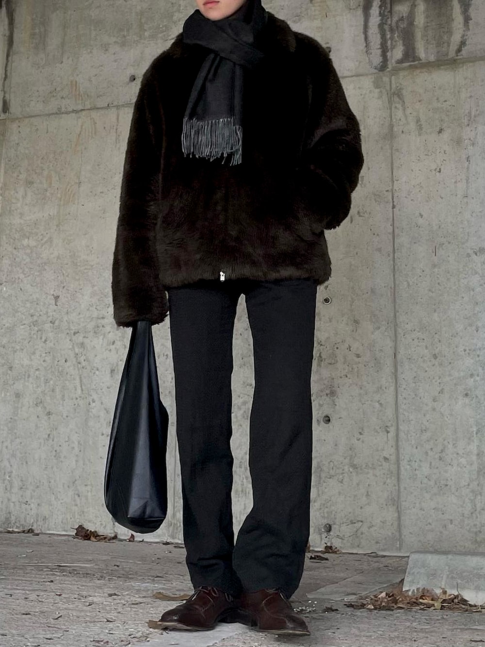 ブラック系のバッグ、ブラウン系のシューズ、ブラック系のマフラーを着用したレディースの冬コーディネートの2枚目の写真