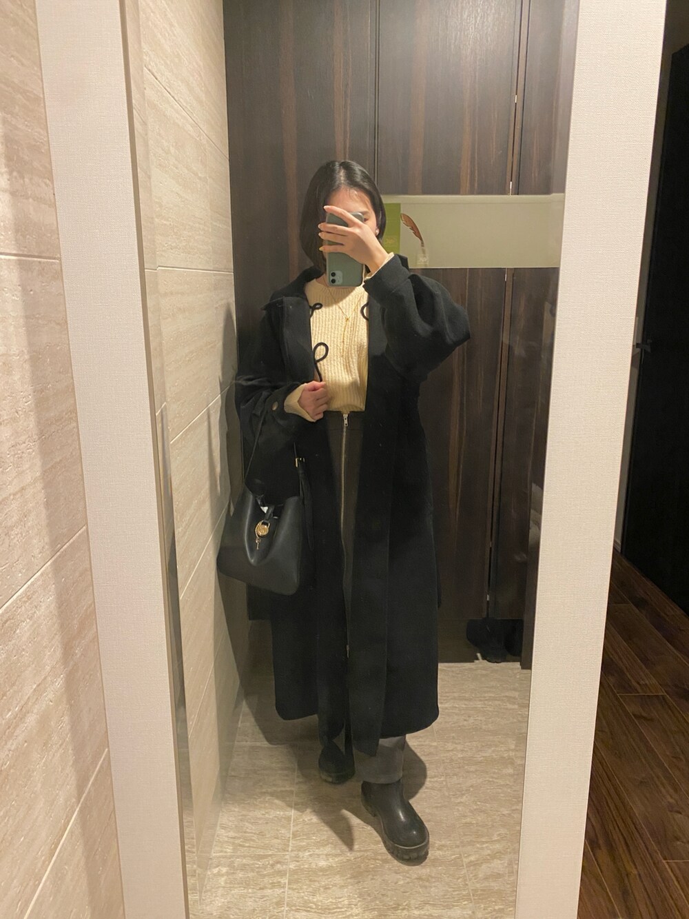 ホワイト系のニット/セーター、グレー系のスカート、ブラック系のブーティを着用したレディースの冬コーディネートの2枚目の写真