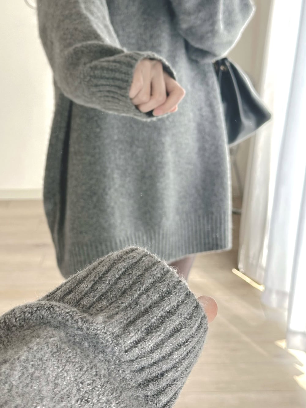 グレー系のワンピース、ブラック系のブーツ、ブラック系のハンドバッグを着用したレディースの冬コーディネートの5枚目の写真