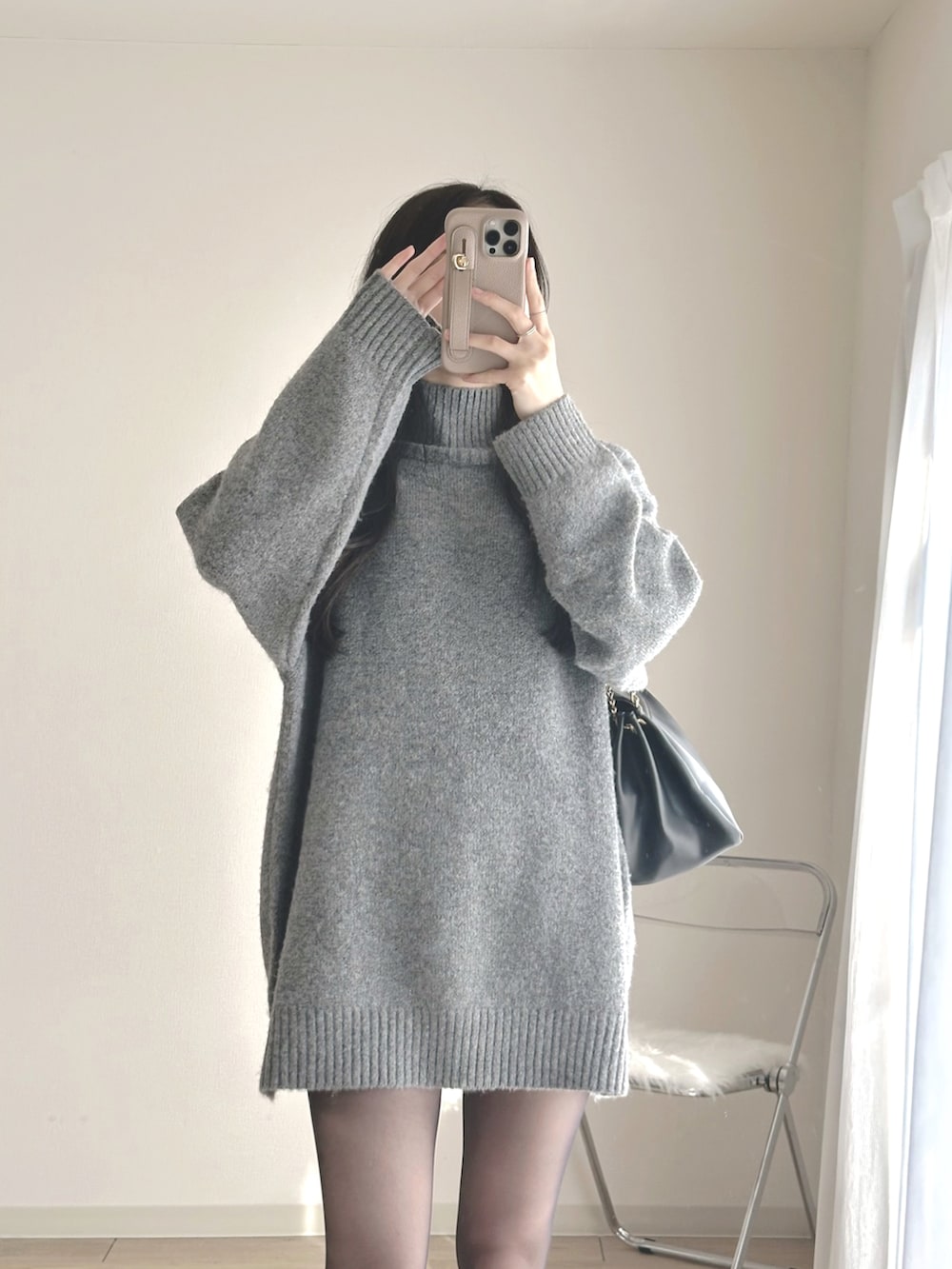 グレー系のワンピース、ブラック系のブーツ、ブラック系のハンドバッグを着用したレディースの冬コーディネートの3枚目の写真