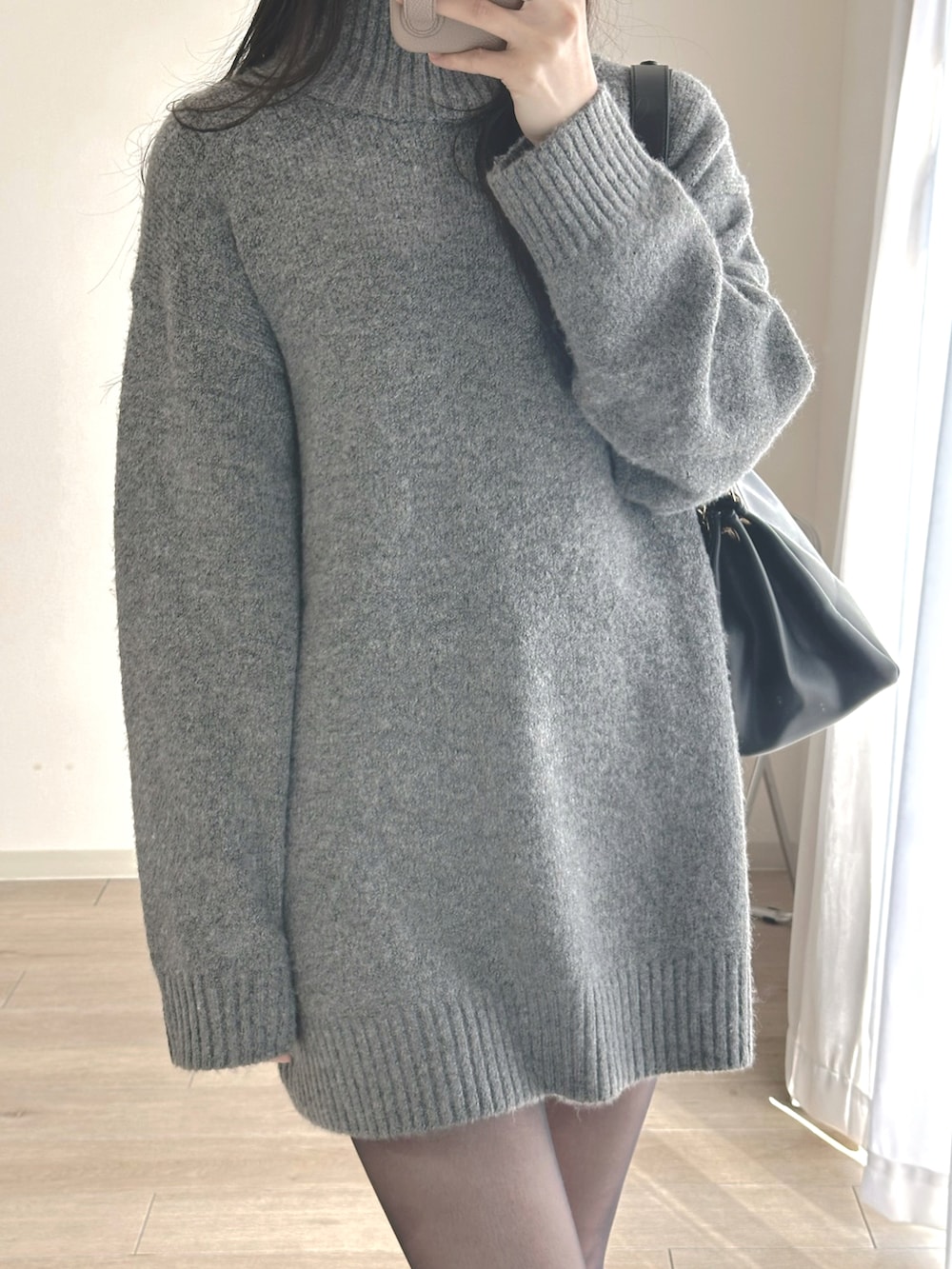 グレー系のワンピース、ブラック系のブーツ、ブラック系のハンドバッグを着用したレディースの冬コーディネートの4枚目の写真