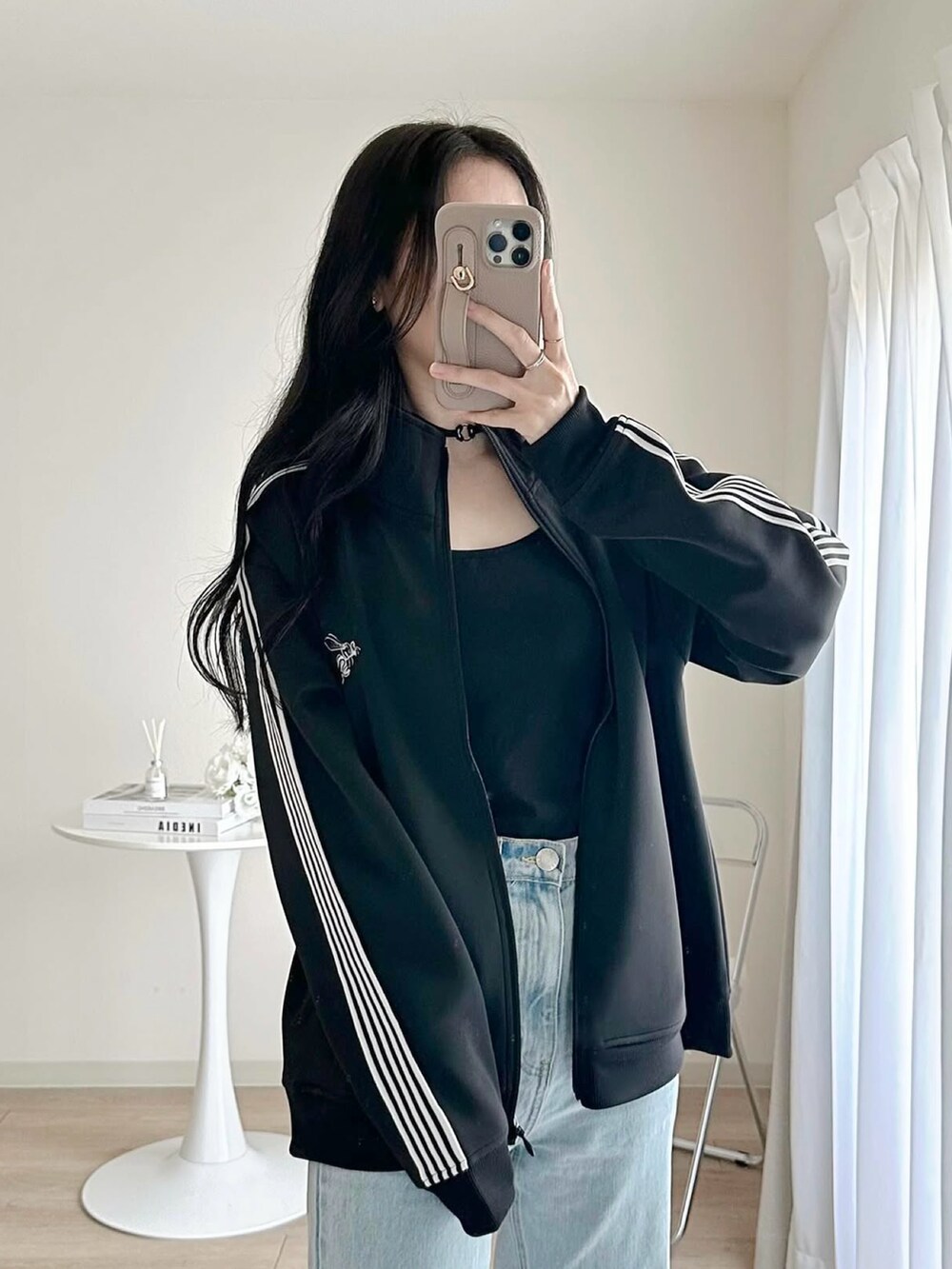 ブラック系のジャージ、ブルー系のデニムパンツ、ホワイト系のスニーカーを着用したレディースの冬コーディネートの3枚目の写真