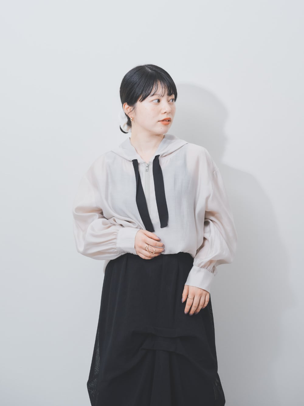 ブラック系のスカート、ベージュ系のパーカーを着用したレディースの夏コーディネートの3枚目の写真