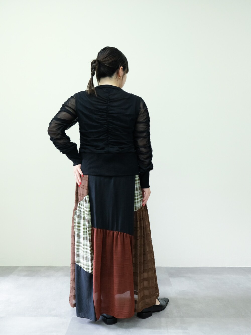 ブラック系のカーディガン/ボレロ、ブラウン系のスカートを着用したレディースの秋コーディネートの2枚目の写真