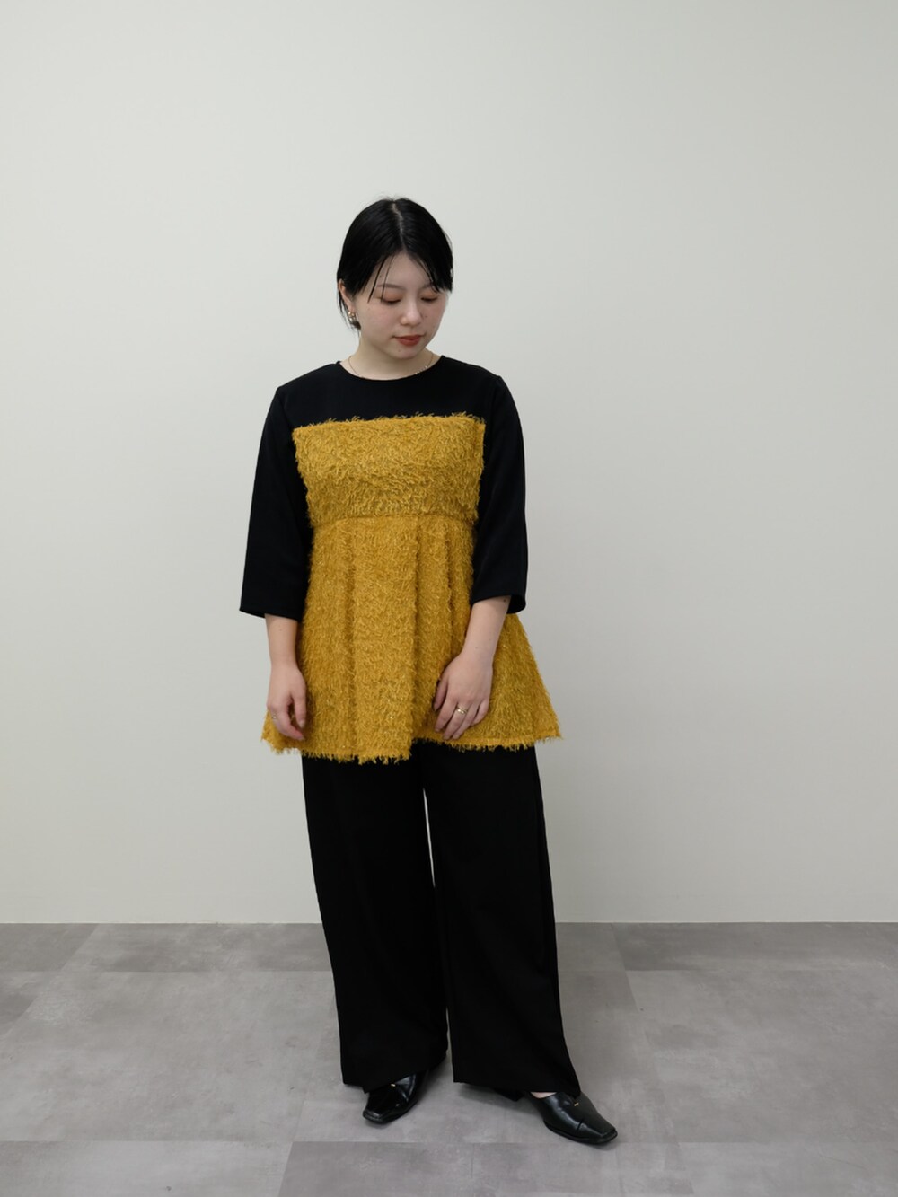 イエロー系のTシャツ/カットソー、ブラック系のスラックスを着用したレディースの秋コーディネートの2枚目の写真