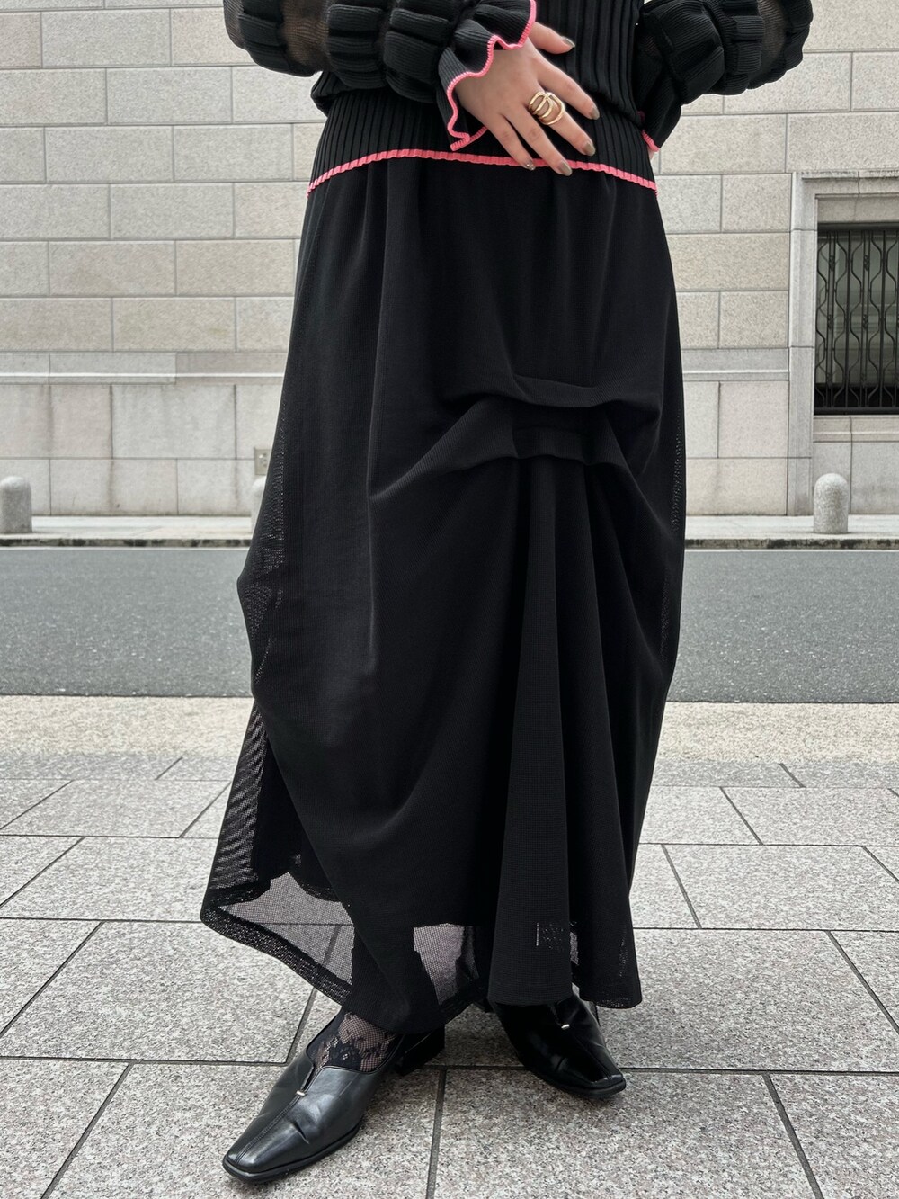 ブラック系のニット/セーター、ブラック系のスカートを着用したレディースの春コーディネートの2枚目の写真