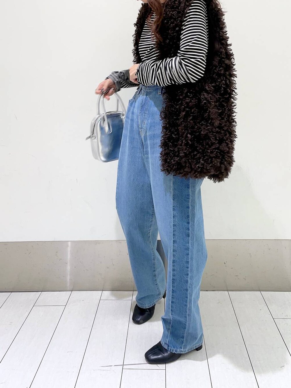 ブラック系のTシャツ/カットソー、ブルー系のデニムパンツ、ブラック系のブーツを着用したレディースの秋コーディネートの4枚目の写真