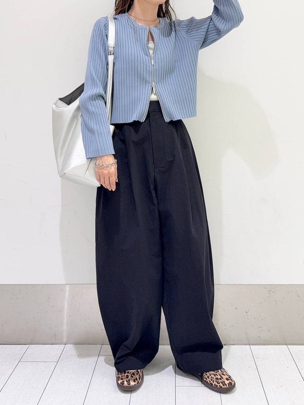 ブルー系のカーディガン/ボレロ、シルバー系のトートバッグ、ブラック系のスラックスを着用したレディースの春コーディネートの4枚目の写真