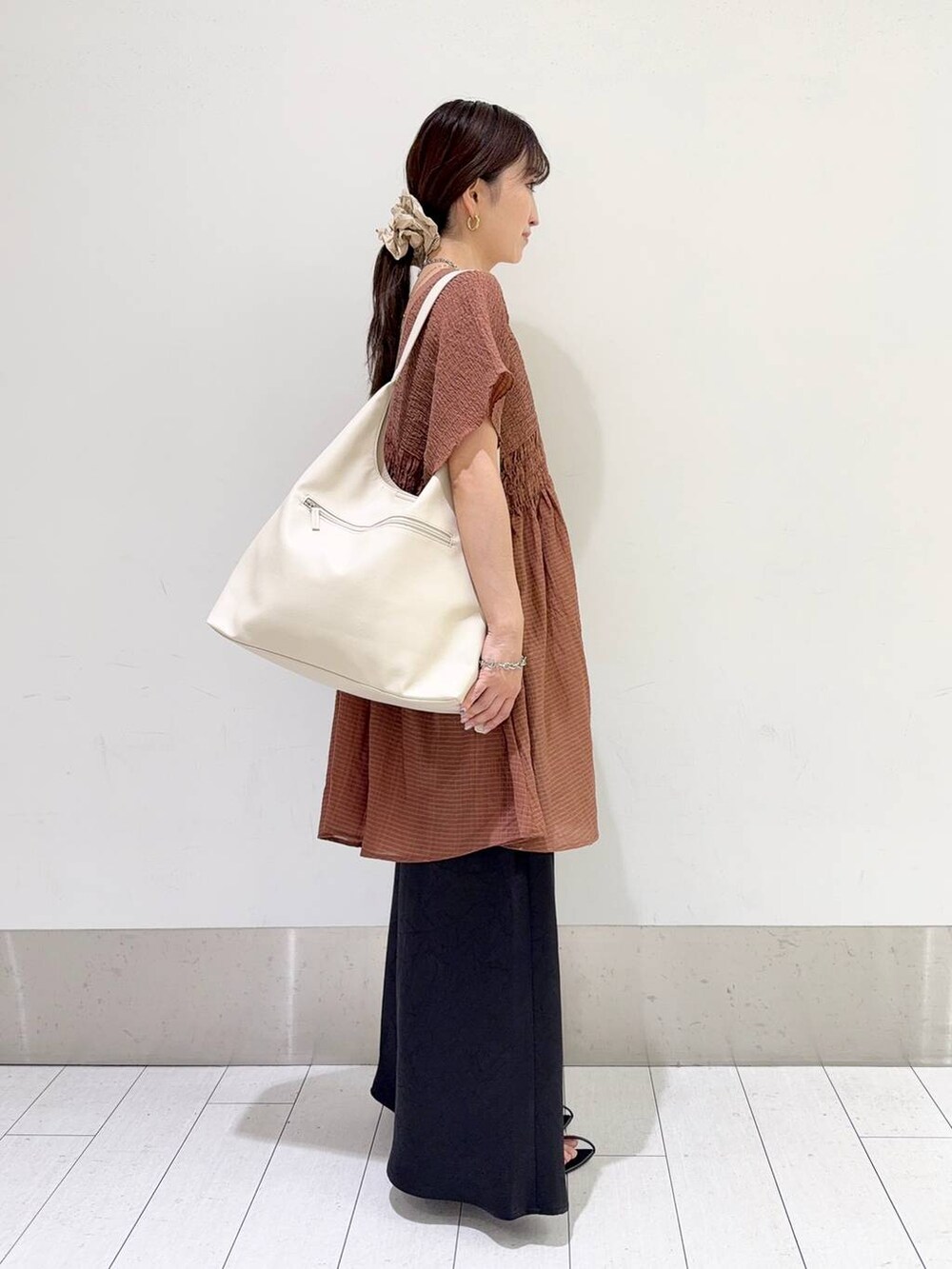 ホワイト系のショルダーバッグ、ブラック系のスカート、ブラウン系のシャツ/ブラウスを着用したレディースの夏コーディネートの2枚目の写真