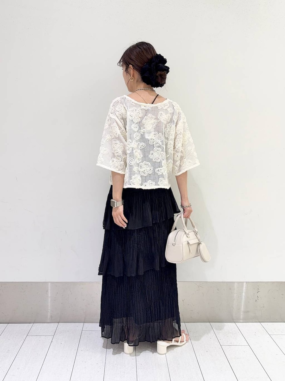 ホワイト系のサンダル、ブラック系のスカート、ホワイト系のショルダーバッグを着用したレディースの夏コーディネートの2枚目の写真