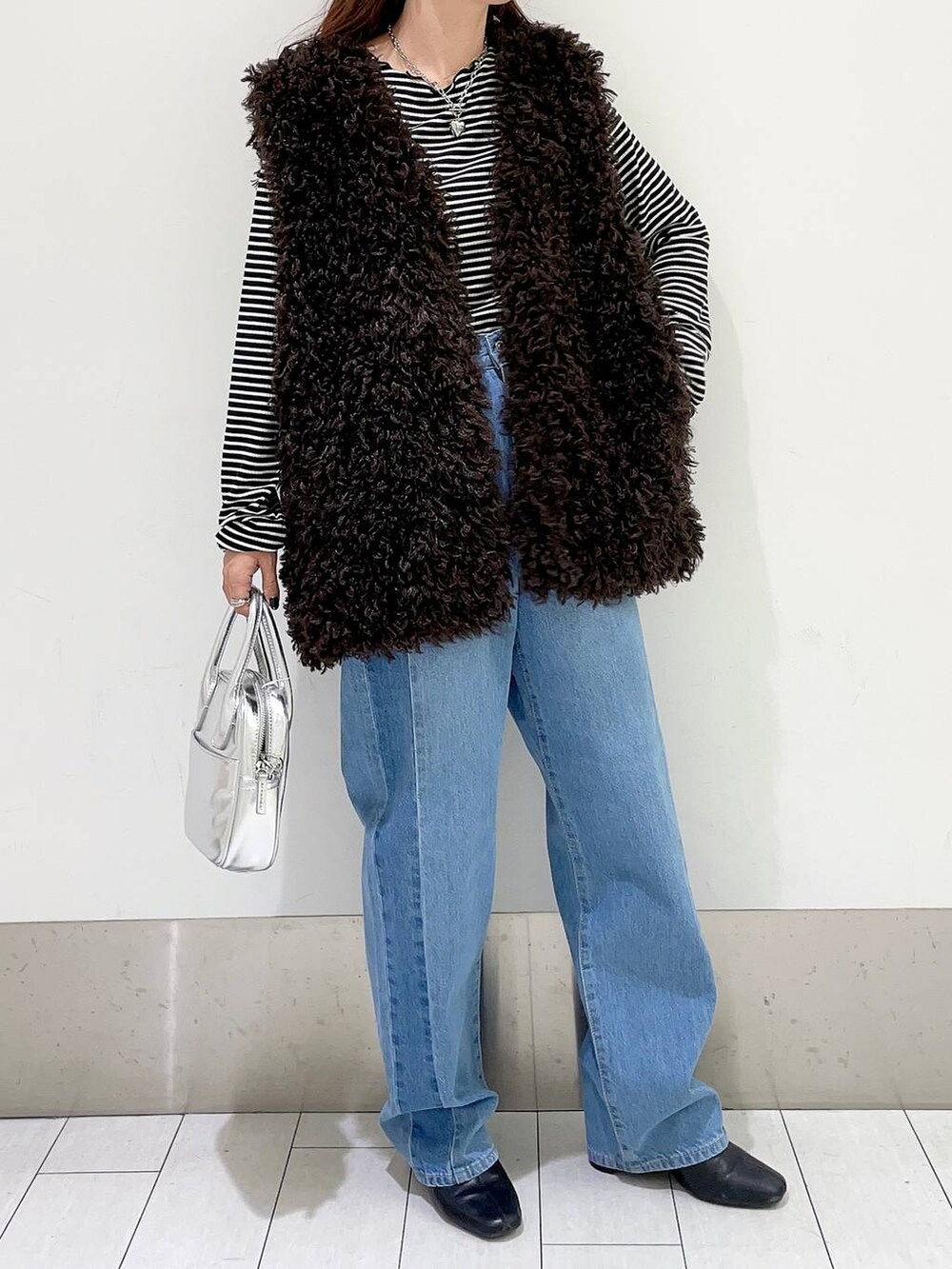 ブラック系のTシャツ/カットソー、ブルー系のデニムパンツ、ブラック系のブーツを着用したレディースの秋コーディネートの5枚目の写真