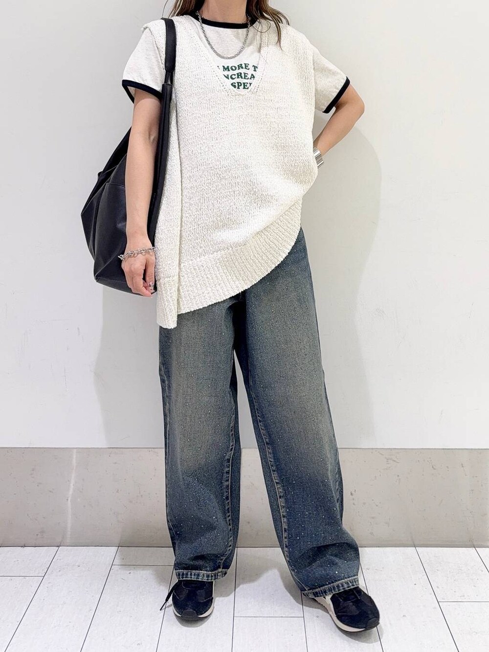 ブルー系のデニムパンツ、ブラック系のトートバッグ、ホワイト系のニット/セーターを着用したレディースの春コーディネートの4枚目の写真