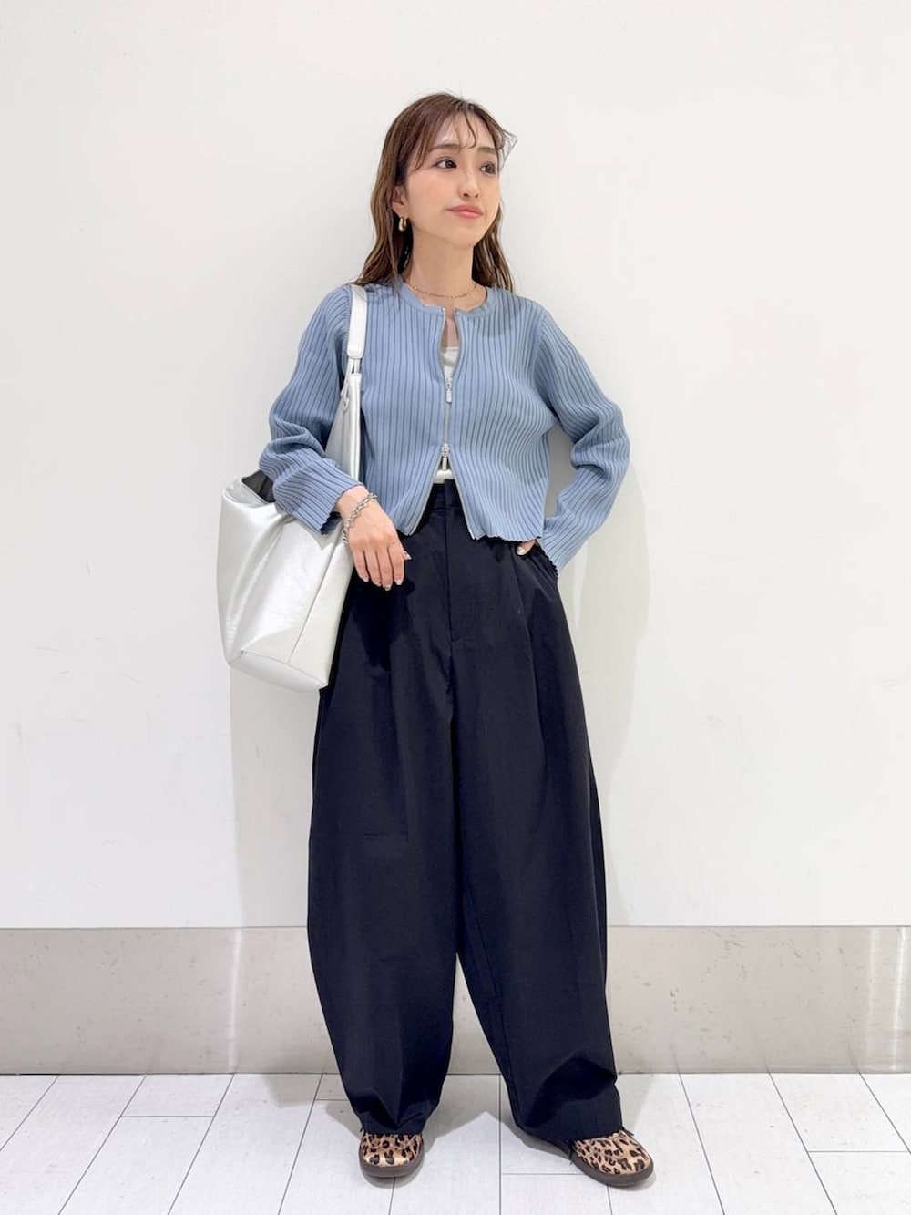 ブルー系のカーディガン/ボレロ、シルバー系のトートバッグ、ブラック系のスラックスを着用したレディースの春コーディネートの2枚目の写真