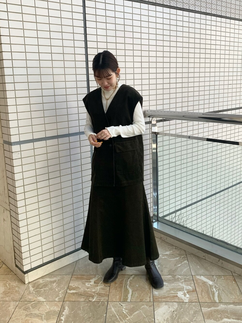 グリーン系のベスト、グリーン系のスカート、ホワイト系のTシャツ/カットソーを着用したレディースの秋コーディネートの2枚目の写真