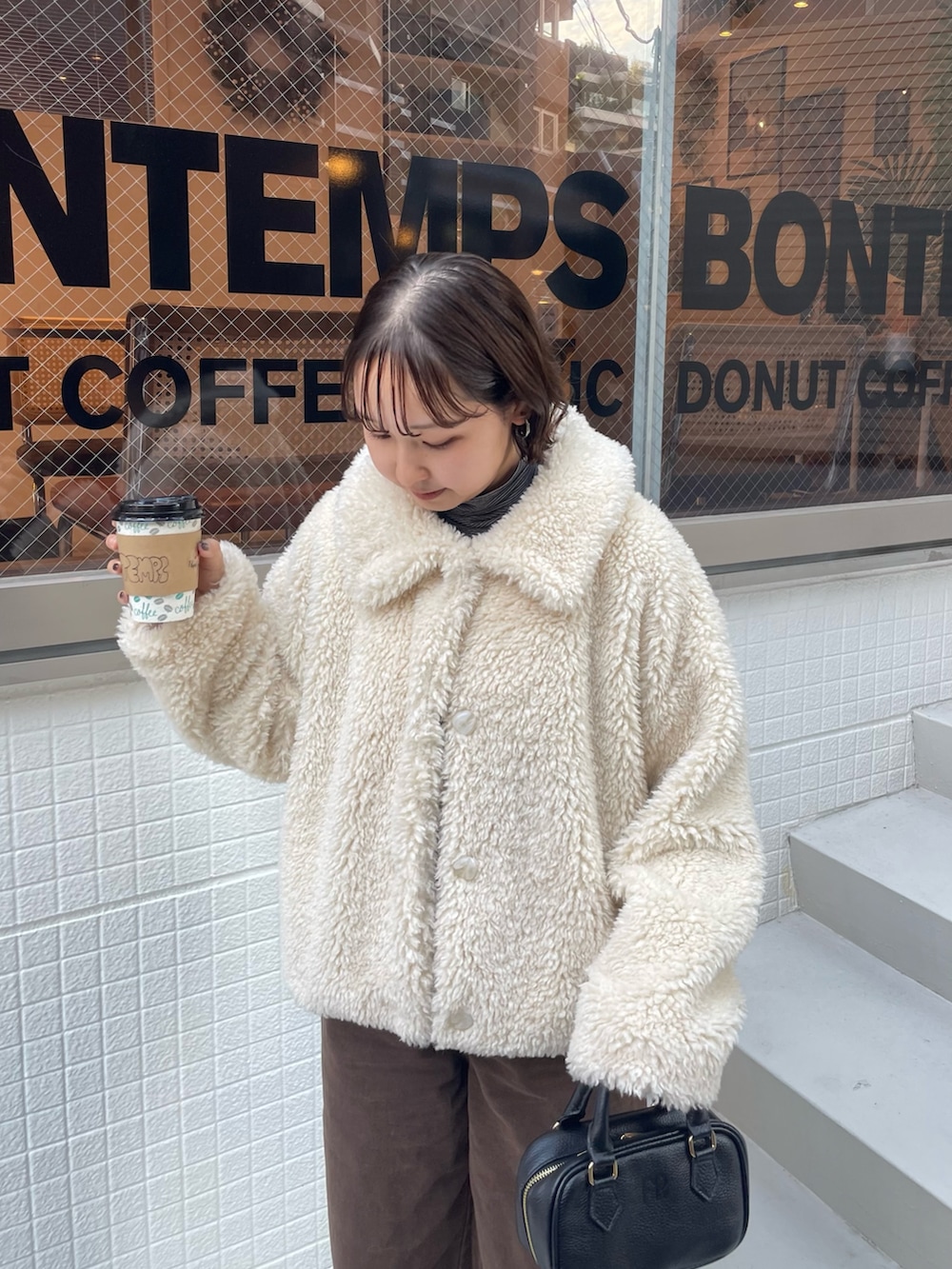 ホワイト系のムートンコート、ブラウン系のその他パンツ、ブラック系のショルダーバッグを着用したレディースの秋コーディネートの3枚目の写真