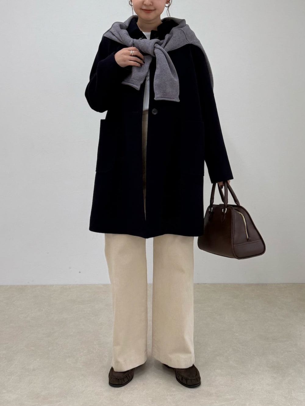 ブルー系のダッフルコート、ベージュ系のその他パンツ、ブラウン系のショルダーバッグを着用したレディースの秋コーディネートの3枚目の写真