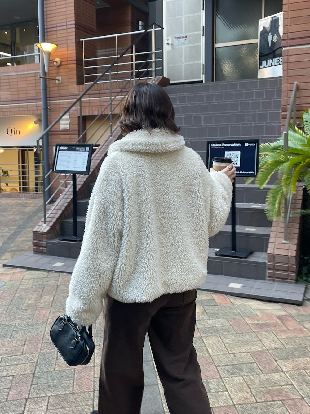 ホワイト系のムートンコート、ブラウン系のその他パンツ、ブラック系のショルダーバッグを着用したレディースの秋コーディネートの5枚目の写真