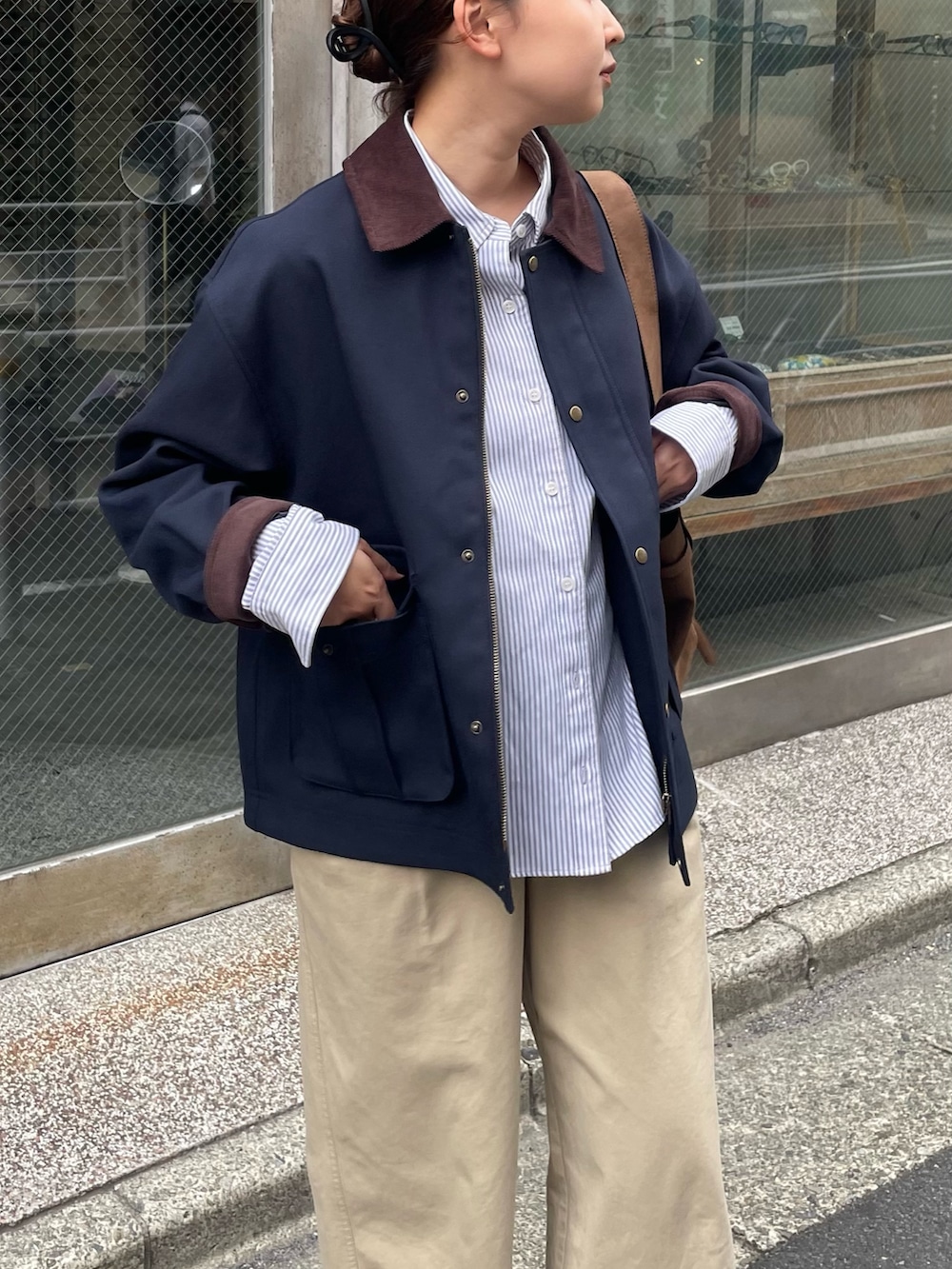 ベージュ系のチノパンツ、ブルー系のブルゾン、ブラウン系のショルダーバッグを着用したレディースの秋コーディネートの3枚目の写真