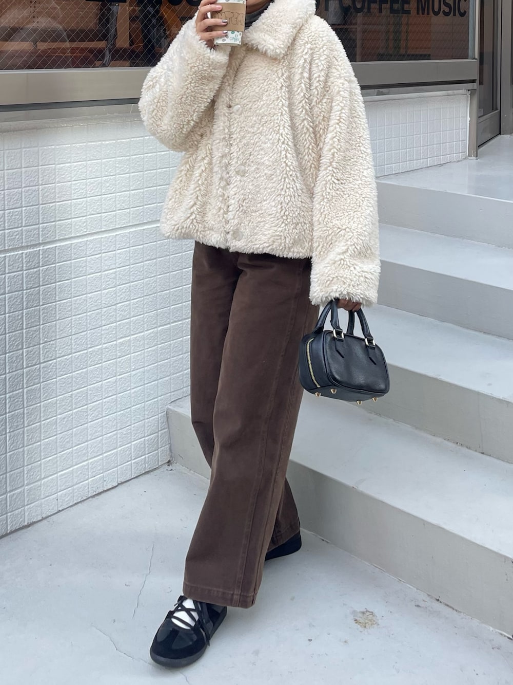 ホワイト系のムートンコート、ブラウン系のその他パンツ、ブラック系のショルダーバッグを着用したレディースの秋コーディネートの4枚目の写真