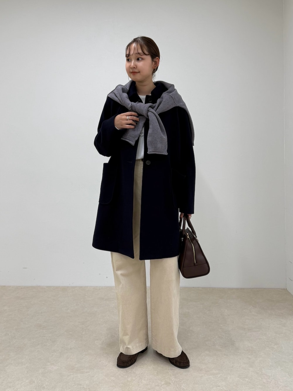 ブルー系のダッフルコート、ベージュ系のその他パンツ、ブラウン系のショルダーバッグを着用したレディースの秋コーディネートの5枚目の写真