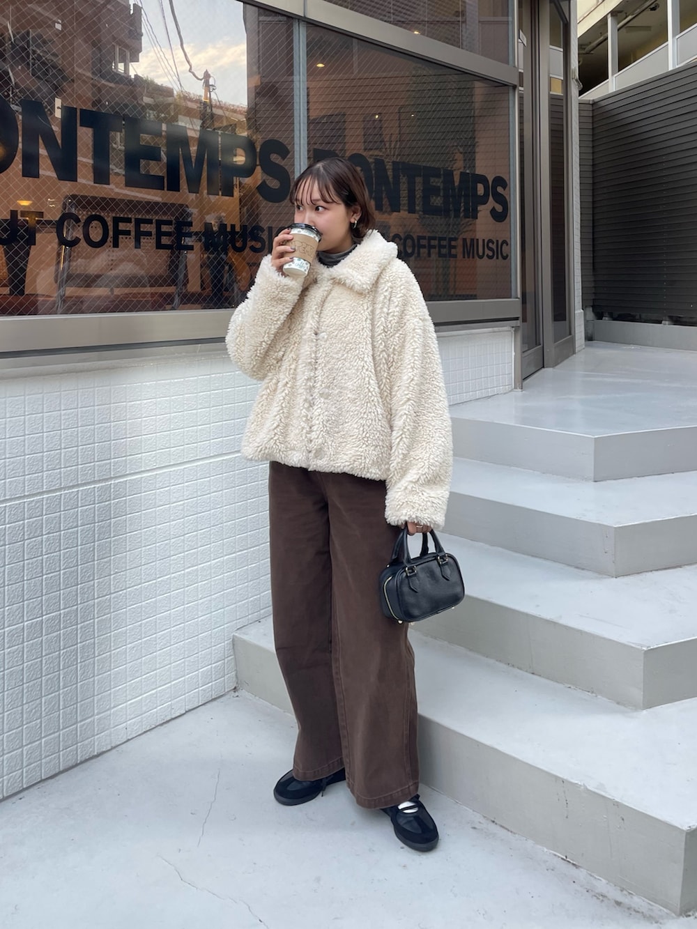 ホワイト系のムートンコート、ブラウン系のその他パンツ、ブラック系のショルダーバッグを着用したレディースの秋コーディネートの6枚目の写真