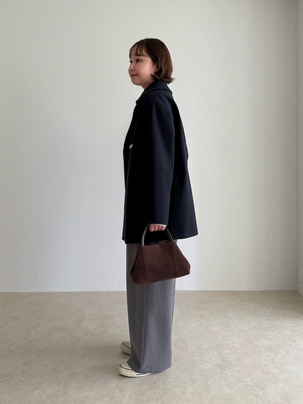 ブルー系のピーコート、グレー系のその他パンツ、ブラウン系のショルダーバッグを着用したレディースの秋コーディネートの3枚目の写真