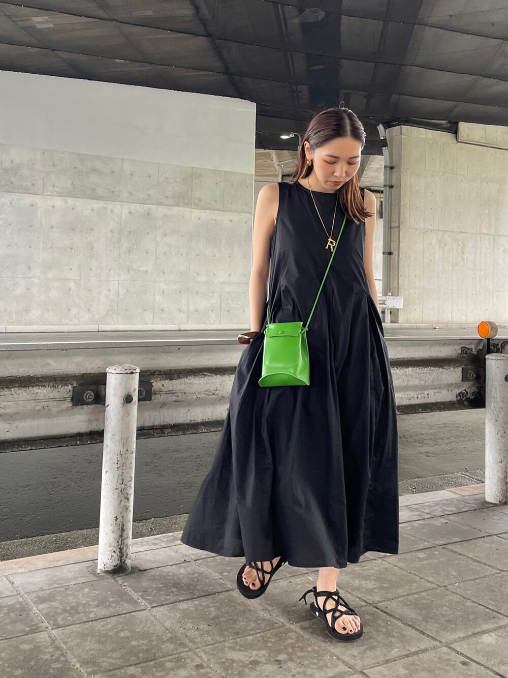 ブラック系のワンピース、ブラック系のサンダル、グリーン系のショルダーバッグを着用したレディースの春コーディネートの2枚目の写真