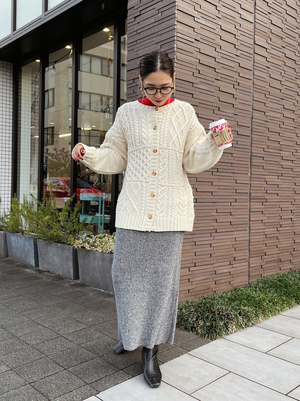 ホワイト系のカーディガン/ボレロ、レッド系のニット/セーター、グレー系のスカートを着用したレディースの冬コーディネートの5枚目の写真